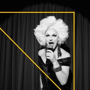 A person in drag performing with a microphone.