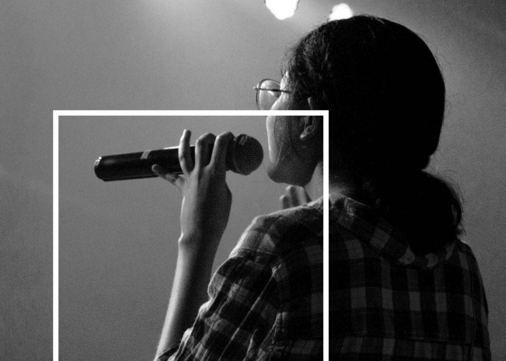 The back of a woman's head as she faces stage lights.